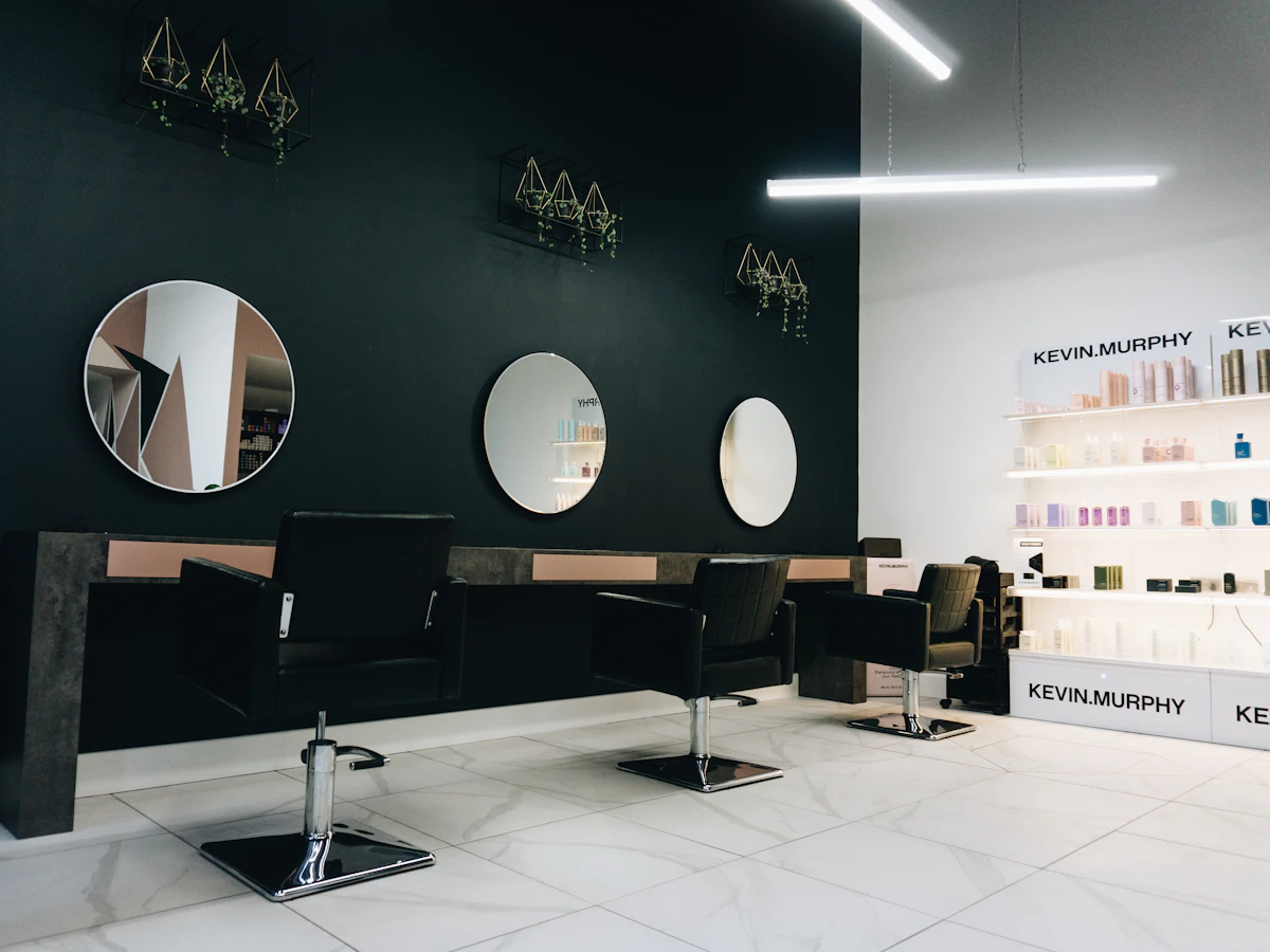 Beispielfoto: Friseursalon mit runden Spiegeln und schwarzen Stühlen